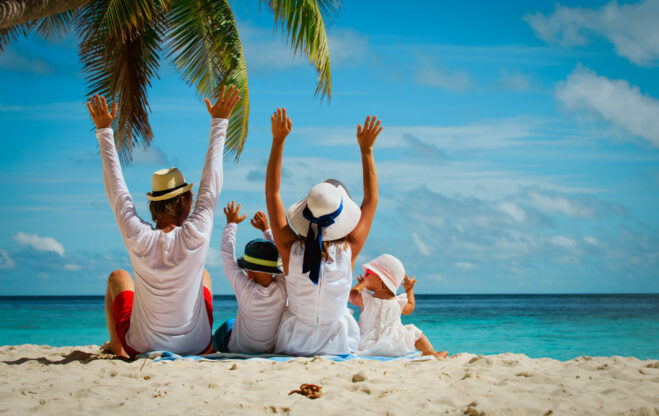 happy family with two kids hands up on tropical beach